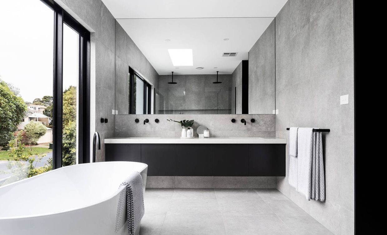 bathroom with large windows overlooking the street, large white bath, double vanity with large mirror