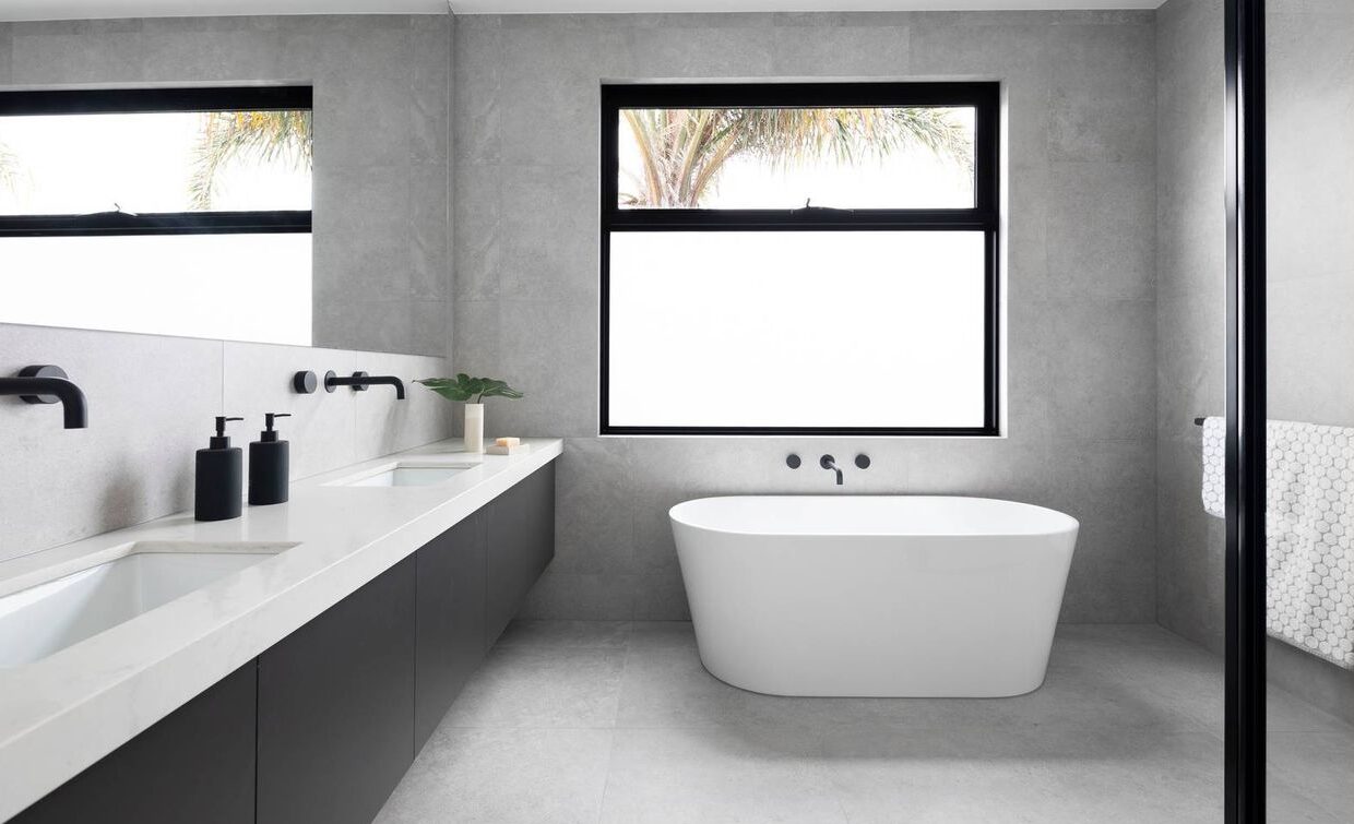large bathroom with tall bath, double vanity, all black accents