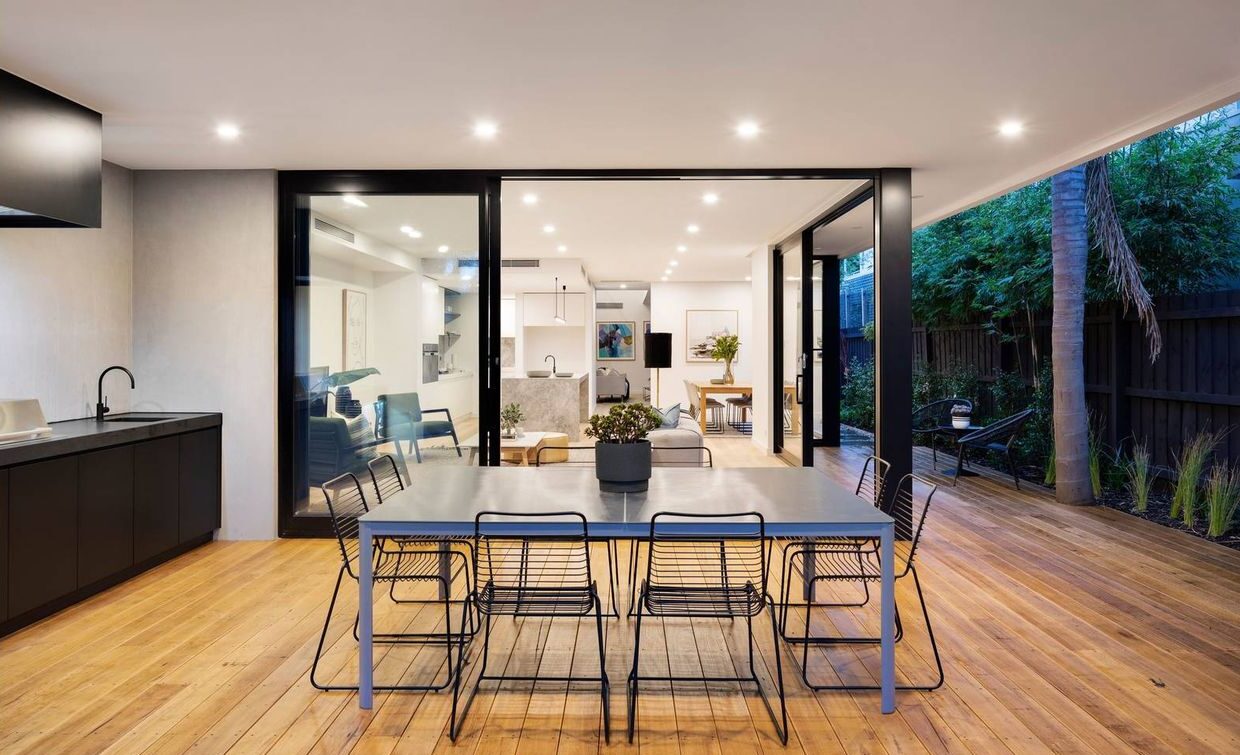 looking at the outdoor setting with table and chairs and kitchen on the left hand side, sliding doors open looking into open living area with all furniture