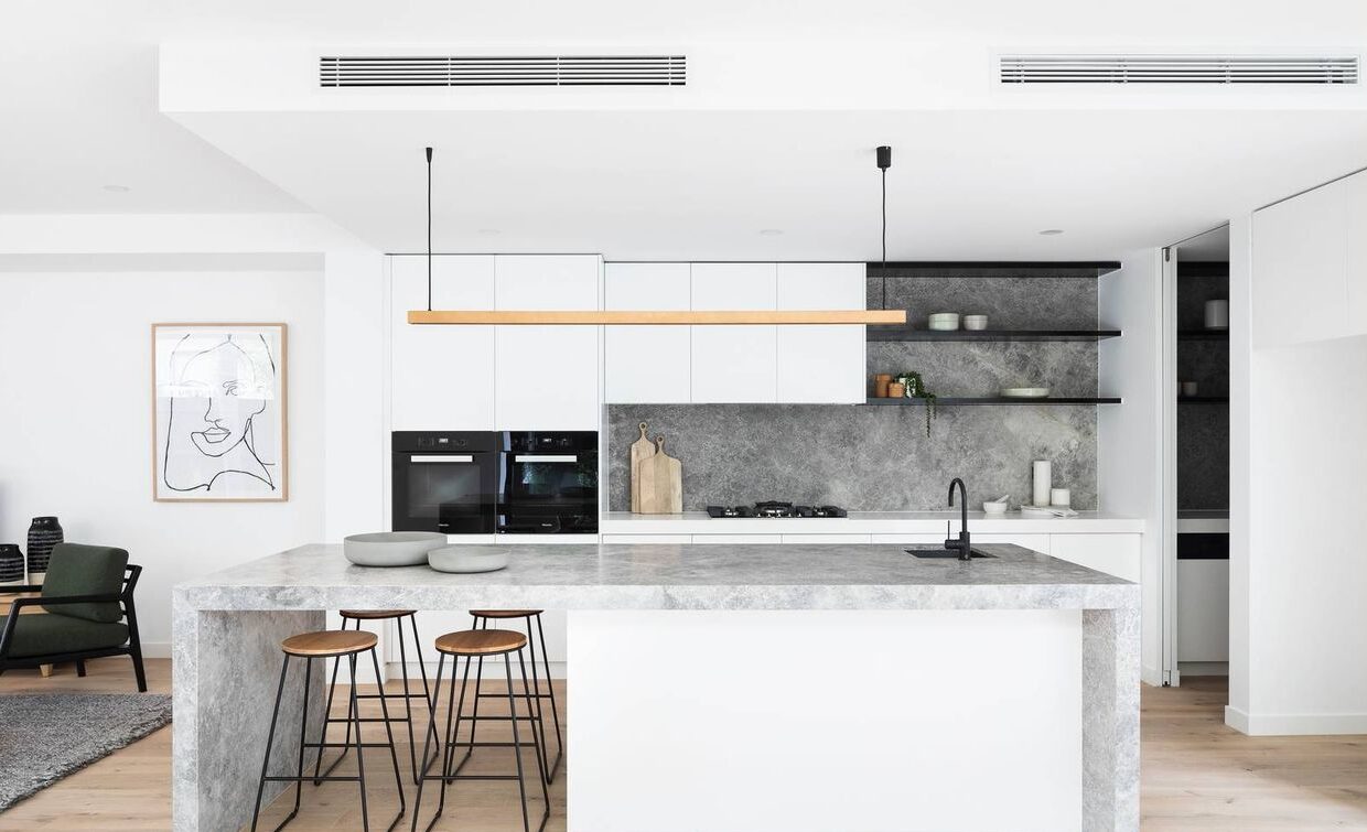 kitchen with 4 stool under the bench, shelving, wooden lighting fixture, cupboards, double ovens and walking pantry on the right hand side