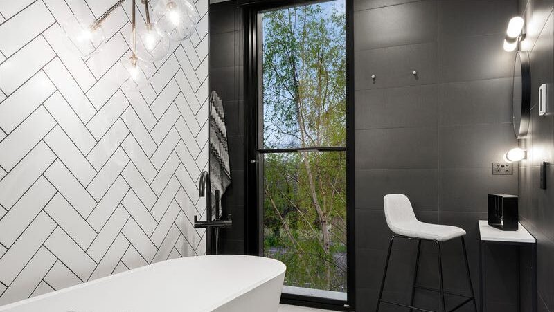66 thomas st brighton east looking over bathtub out the window, tiled feature wall behind bathtub, feature light hanging over bath